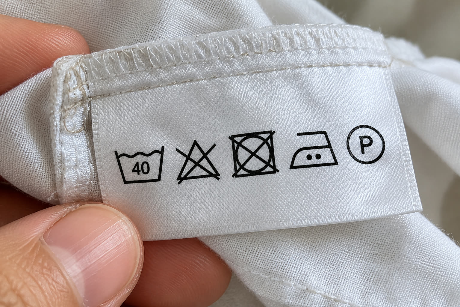 Label perawatan pada sebuah blus: cuci maksimal 40°C, jangan diputihkan, jangan dikeringkan dengan mesin pengering, setrika dua titik (panas sedang), dan boleh dry clean dengan pelarut kode P.